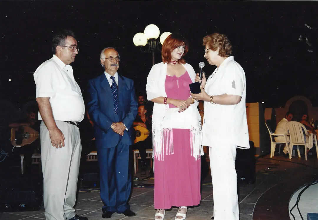 Four adults engaged in conversation outdoors at night.