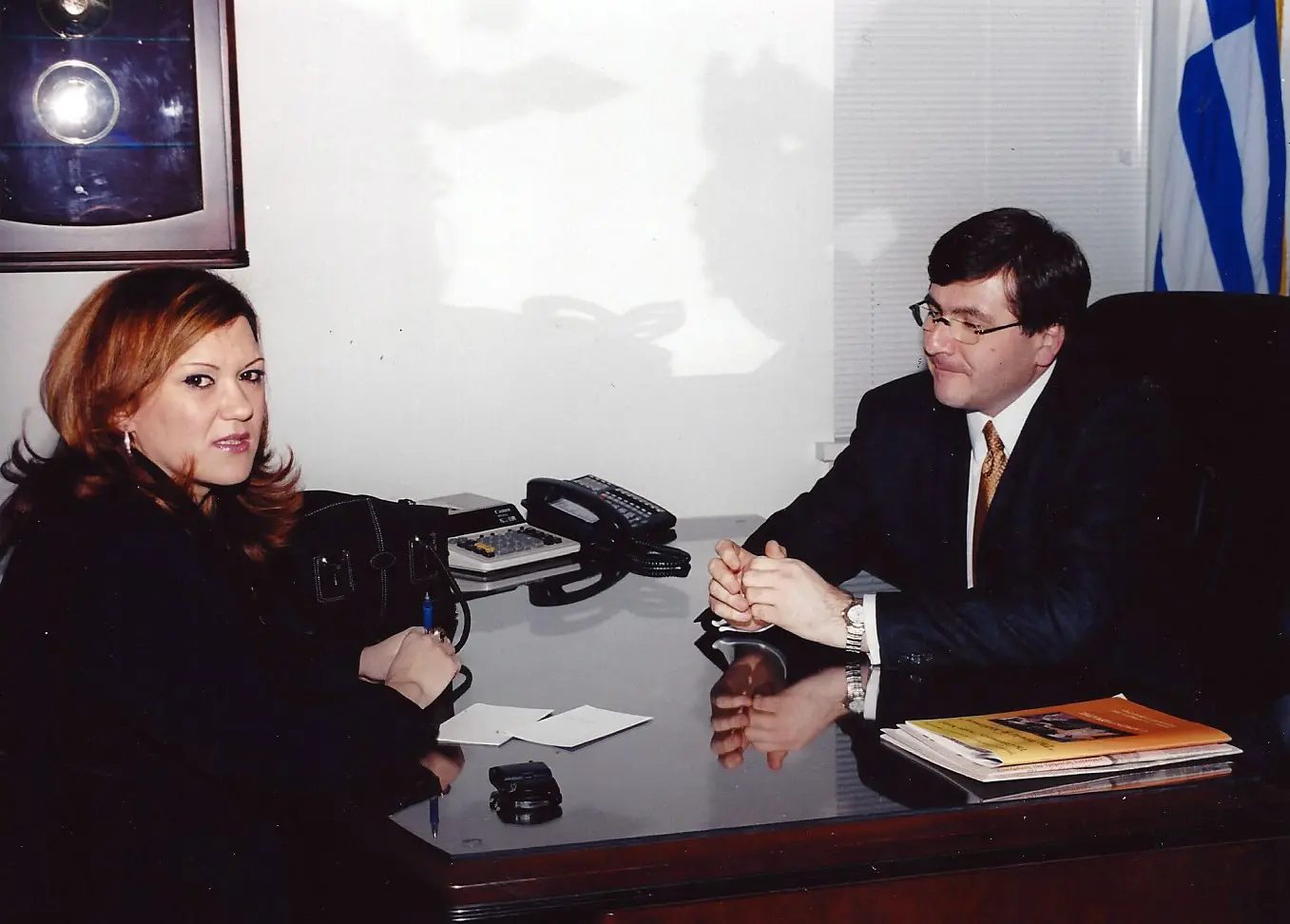 Two professionals having a serious discussion across a desk in an office.