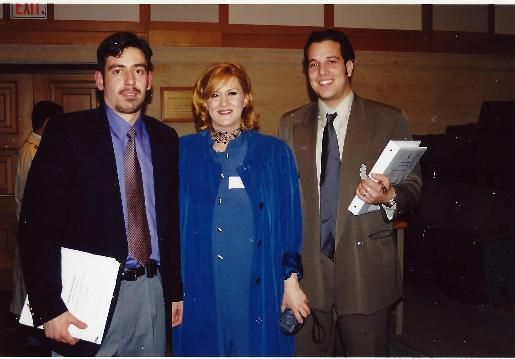 Three professionally dressed people posing indoors.
