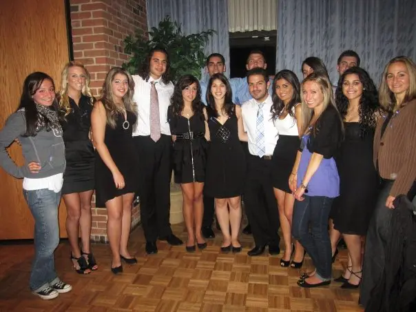 A group of young adults dressed formally, posing indoors.