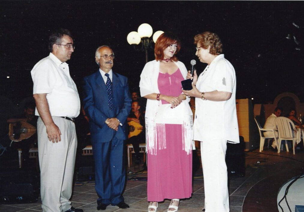 Four adults engaged in conversation outdoors at night.