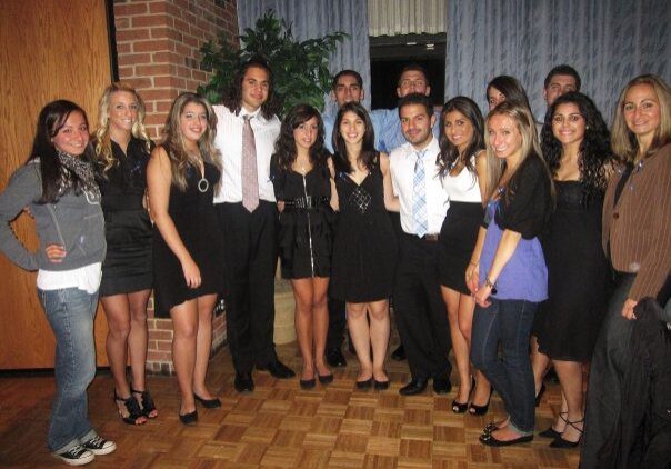 A group of young adults dressed formally, posing indoors.